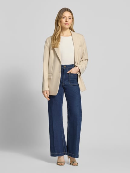 Frauenmodel trägt Top mit Rundhalsausschnitt von Christian Berg Woman Selection in Weiß, kombiniert mit beigem Blazer und blauer Jeans, Ganzkörperansicht von vorne.