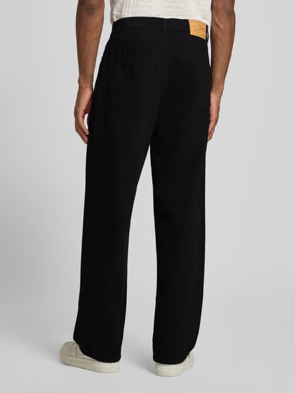 Männermodel trägt Loose Fit Jeans im 5-Pocket-Design Modell 'Roi' von Les Deux aus Reine Baumwolle, Ausgestellter Schnitt, Ganzkörperansicht Rückansicht.