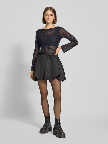 Frauenmodel trägt Slim Fit Longsleeve mit floralem Pailettenbesatz von Gina Tricot aus elastischem, semitransparentem Material-Mix, U-Boot-Ausschnitt und ausgestellte Ärmel, Ganzkörperansicht von vorne.