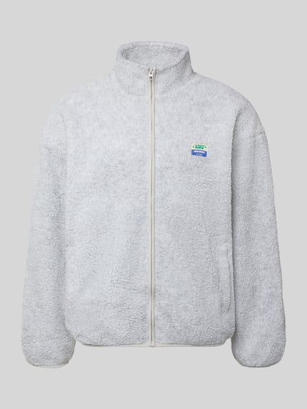 Produktfoto, Sweatjacke mit Logo-Patch Modell 'HOKTOWN' von AMERICAN VINTAGE in hellgrauer Fleece-Optik mit Reißverschluss, Langarm, stehender Kragen, strukturierte unifarbene Oberfläche, seitliche Eingrifftaschen, Regular Fit und elastischem Bund.