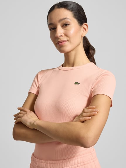 Vrouwenmodel draagt Slim Fit T-shirt uit puur katoen van Lacoste Sport, look: effen, logostitching, ronde hals, korte mouw, rib. Nahaufnahme Oberkörper.
