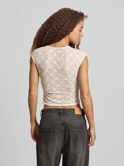 Vrouwenmodel draagt T-Shirt uit kant met rimpeling aan de zijnaad van REVIEW, elastische materiaalmix, aansluitende fit, rugaanzicht.
