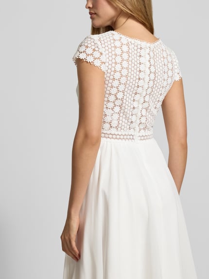 Kobiece modelka nosi Brautkleid mit floraler Spitze od LUXUAR FASHION, białe, gładkie, z kwiatową koronką, dopasowany krój, rozkloszowana spódnica, widok całej sylwetki z tyłu.