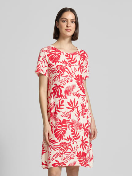 Vrouwenmodel draagt Relaxed Fit jurk uit viscosemix model 'Tara' van ZABAIONE, rood-wit bladmotief, ronde hals, korte mouwen, vooraanzicht bovenlichaam.