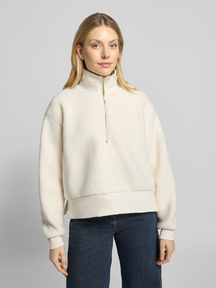 Frauenmodel trägt Regular Fit Sweatshirt mit Troyer-Kragen von Christian Berg Woman aus cremefarbenem Teddyfell, Reißverschluss, Nahaufnahme Oberkörper.