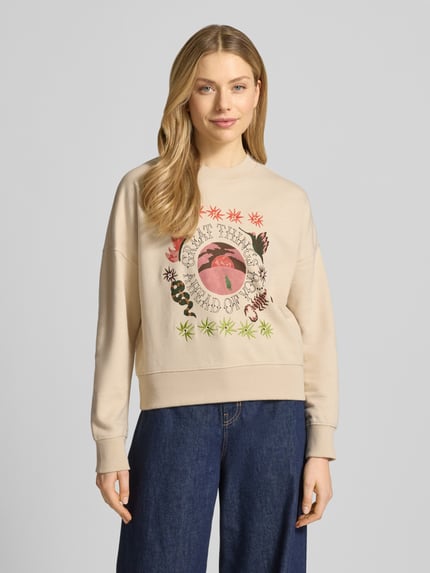 Frauenmodel trägt Relaxed Fit Sweatshirt mit floralem Stitching von Scotch & Soda aus reiner Baumwolle, Rundhalsausschnitt, Motiv-Print, elastische Abschlüsse, Ganzkörperansicht von vorne.