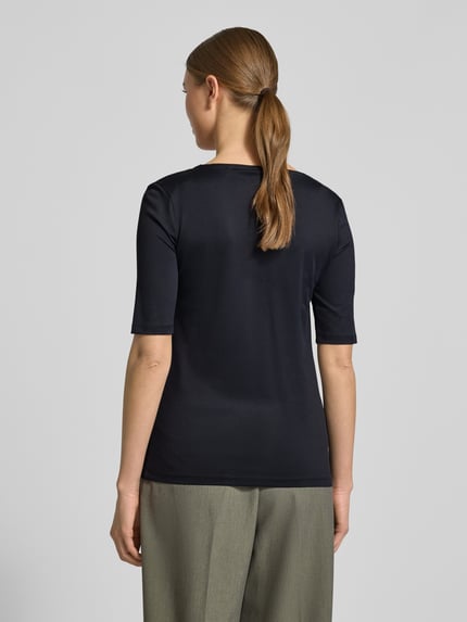 Kobiece modelka nosi Slim Fit T-Shirt mit Rundhalsausschnitt von Christian Berg Woman, elastyczna mieszanka materiałów, krój slim fit, okrągły dekolt, rękaw o dł. 1/2, długość tyłu w rozmiarze S: 52 cm, widok całej sylwetki z tyłu.