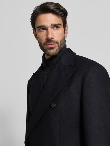 Männermodel trägt Mantel aus Woll-Mix mit Reverskragen Modell 'Richborne' von JOOP! Collection mit Zweireiher, Nahaufnahme Oberkörper. Gerader Schnitt, Stretch-Anteil, Pattentaschen, Knopfverschluss, Rückenlänge 103 cm, Schulterbreite 47 cm, Brustweite 53 cm, Ärmellänge 67 cm.