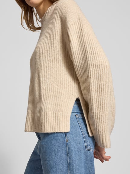 Vrouwenmodel draagt Oversized Strickpullover mit gerippten Abschlüssen Modell 'SIGGA' van JJXX, beige, ribbelstructuur, zijaanzicht, detailopname bovenlichaam, materiaal-mix met lanaanwoll.
