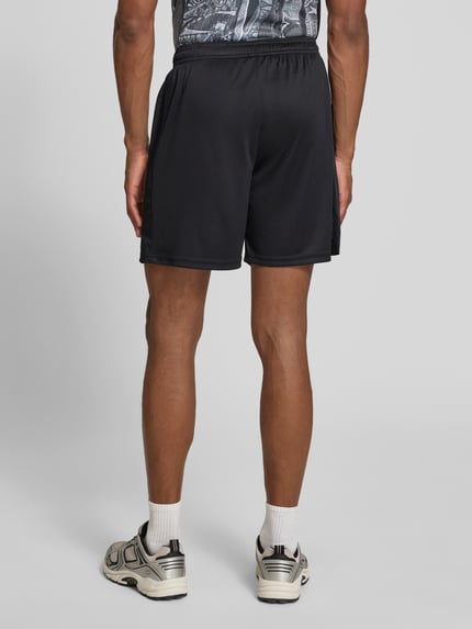 Männermodel trägt Relaxed Fit Shorts mit Logo-Print von COLUCCI, elastischer Bund, Motiv-Stitching, schwarze Farbe, Ganzkörperansicht Rückansicht.