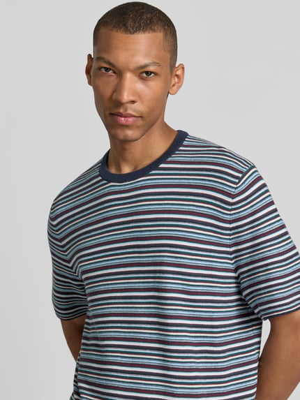 Męski model nosi T-Shirt mit Rundhalsausschnitt von MCNEAL, bawełna, krój regular fit, granatowe i niebieskie paski, długość tyłu 70 cm, długość rękawa 25 cm, zbliżenie na górną część ciała