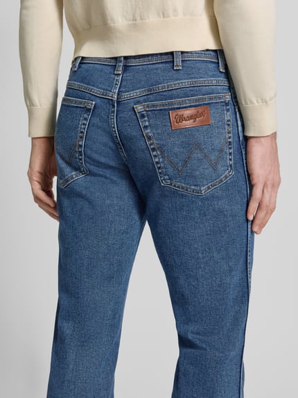 Mannenmodel draagt Straight Fit Jeans im 5-Pocket-Design Modell 'Texas' van Wrangler in katoenmix met stretch, recht model, detailopname rugzijde. Context: heren straight jeans van Wrangler, katoenmix met stretch, recht model, model 'Texas', 5-pocketmodel, knoop- en ritssluiting, bandwijdte bij maat 32/32: 41 cm, binnenbeenlengte bij maat 32/32: 79 cm.