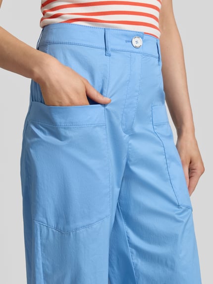 Frauenmodel trägt Wide Fit Stoffhose mit aufgesetzten Taschen von Marc Cain, hellblauer Baumwoll-Mix, Nahaufnahme Oberkörper.