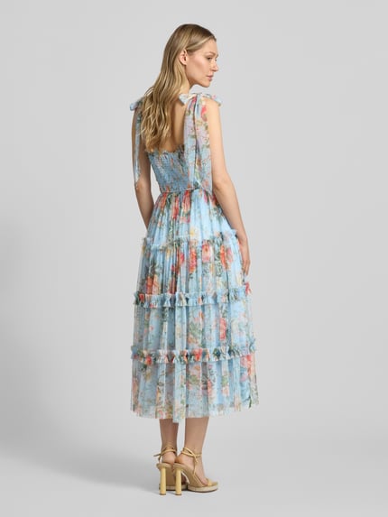 Frauenmodel trägt Knielanges Cocktailkleid mit Smok-Details von LACE & BEADS aus buntem Mesh, A-Linie, Stufen-Look, Schnürung, Ganzkörperansicht Rückansicht.