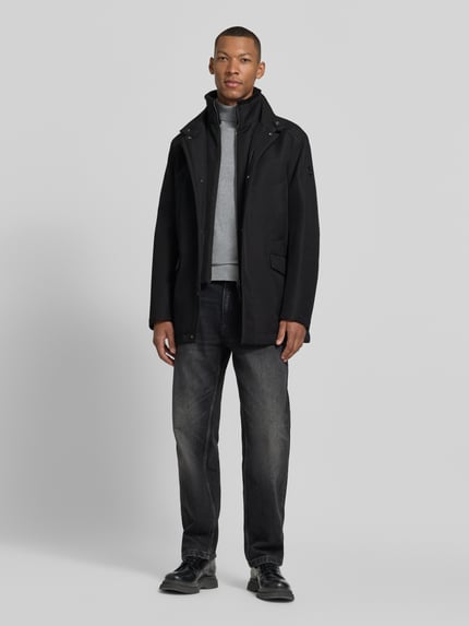 Männermodel trägt Kurzmantel Modell 'DARRY' von JOOP! in Schwarz, Stehkragen, Struktur, lange Ärmel, Pattentaschen, Ganzkörperansicht von vorne.