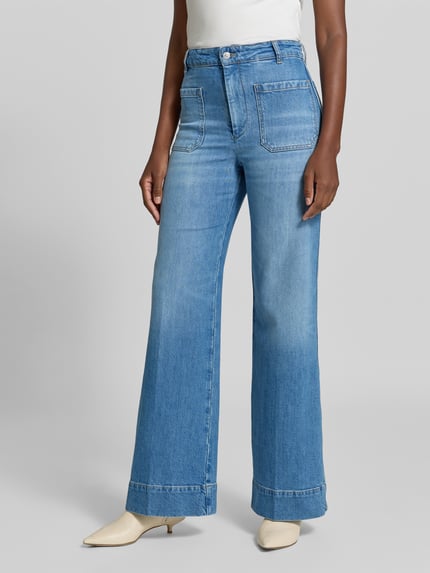 Frauenmodel trägt Wide Fit Jeans aus Baumwoll-Mix von Victoria Beckham w jasnoniebieskim kolorze z nakładanymi kieszeniami, zapięcie na guzik i zamek błyskawiczny, długość wewnętrzna nogawki w rozmiarze 27/32: 83 cm, szerokość w rozmiarze 27/32: 36 cm, mieszanka bawełny, krój wide fit, całkowita długość nogawek, nakładane kieszenie z tyłu, widoczne faktury dżinsu, Ganzkörperansicht von vorne.