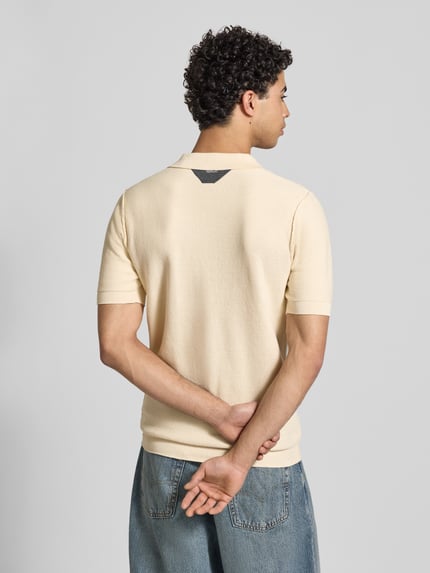Männermodel trägt Slim Fit Poloshirt in Strick-Optik von Replay, reine Baumwolle, gerippte Abschlüsse, Rückenansicht, Ganzkörperansicht.