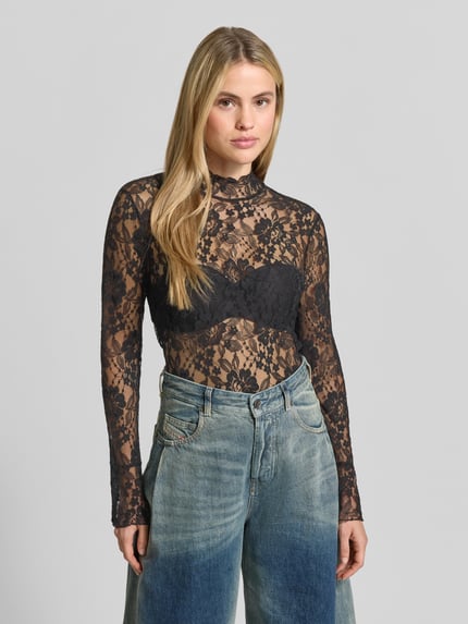 Frauenmodel trägt Langarmbluse aus Spitze Modell 'MEENA' von BAUM & PFERDGARTEN, schwarzes florales Allover-Muster, hochgeschlossen, Nahaufnahme Oberkörper.