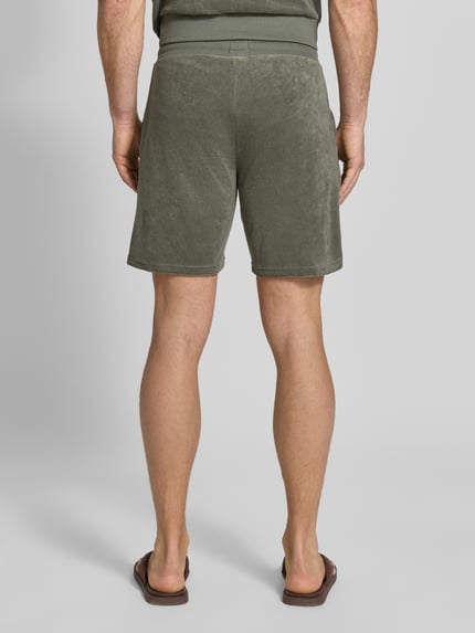 Męski model nosi Regular Fit Sweatshorts aus Baumwoll-Mix Modell 'TERRANCE' od HUGO, kolor jednolity, bawełniany miks, elastyczny pas z troczkiem, boczne kieszenie, metka z logo, widok całej sylwetki od tyłu.