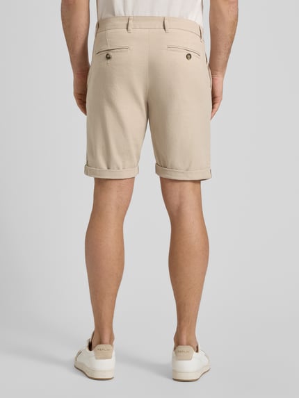 Männermodel trägt Slim Fit Chinoshorts aus Baumwoll-Mix Modell 'SLIM-LUTON' von SELECTED HOMME, Optik: Unifarben, Ganzkörperansicht Rückansicht.