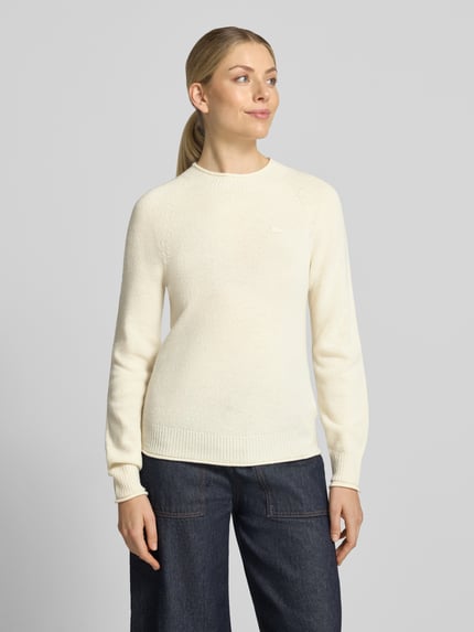 Frauenmodel trägt Regular Fit Pullover aus reiner Wolle von Lacoste in Cremeweiß, strukturierte Oberfläche, kombiniert mit dunkler Jeans, Ganzkörperansicht von vorne. Damen Pullover von Lacoste.