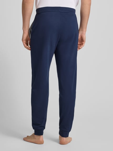 Männermodel trägt dunkelblaue Sweatpants mit elastischem Bund von Christian Berg Men, Baumwolle, gerade Passform, Ganzkörperansicht Rückansicht.