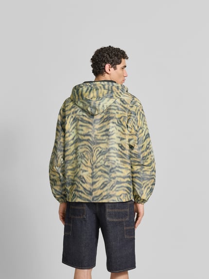 Mannenmodel draagt Regular Fit Windbreaker met capuchon van Kenzo, all-over dierenprint, borstzakken, ritssluiting, ruglengte maat M 69 cm, schouderbreedte 60 cm, mouwlengte 64 cm. Ganzkörperansicht Rückansicht.