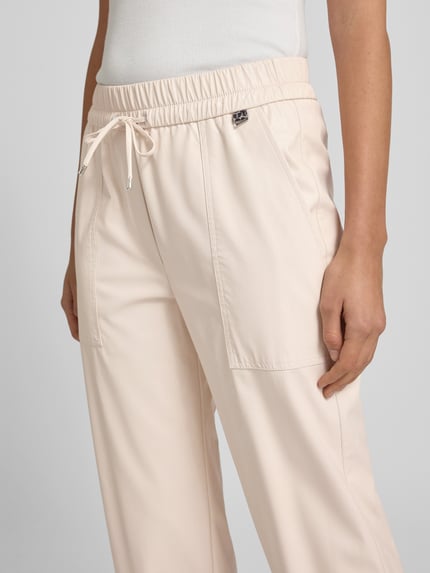 Frauenmodel trägt Jogpants aus Viskose-Mix mit elastischem Bund von Marc Cain in Beige, Regular-Fit, Tunnelzug, Eingrifftaschen, Nahaufnahme Oberkörper.
