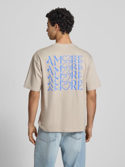 Männermodel trägt Regular Fit T-Shirt aus reiner Baumwolle Modell 'CASPIAN AIRFLEX AMORE' von Only & Sons in Beige mit blauem Print, unifarben, kühlend, atmungsaktiv, Ganzkörperansicht Rückansicht.