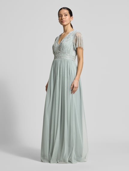 Frauenmodel trägt Regular Fit Abendkleid mit floralem Ziersteinbesatz von Christian Berg Cocktail in Mintgrün, semitransparent, V-Ausschnitt, Kurzärmelig, mit Unterrock, Ganzkörperansicht von vorne. Rückenlänge 156 cm, Brustweite 40 cm, Ärmellänge 22 cm.