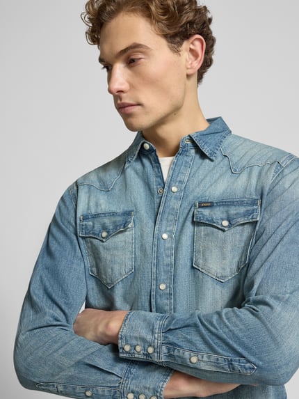Męski model nosi Freizeithemd in Denim-Optik od Polo Ralph Lauren w kolorze niebieskim, bawełna, regular fit, detal z logo, zbliżenie górnej części ciała.