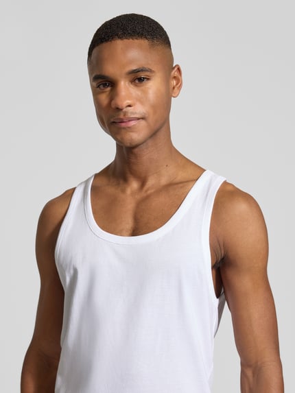 Męski model nosi biały Tank Top z bawełny i elastanu, dopasowany krój, szerokie ramiączka, detal z logo, 3-pak, model 'Modern' od BOSS, zbliżenie na górną część ciała