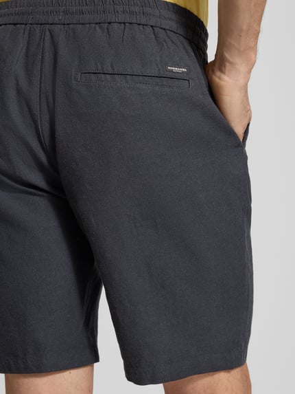 Männermodel trägt Shorts aus Baumwoll-Leinen-Mix Modell 'FAVE' von Scotch & Soda in Dunkelgrau, elastischer Bund, Detailaufnahme Rückansicht. Regular Fit, Bundweite 42 cm, Innenbeinlänge 21 cm (Größe 32).