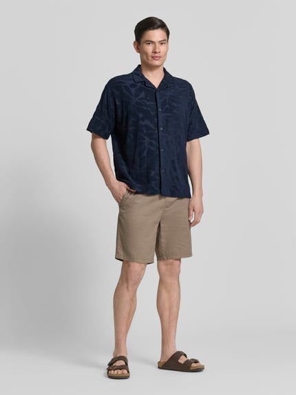 Männermodel trägt Regular Fit Freizeithemd aus Baumwoll-Mix Modell 'WE_FLOWER' von BOSS Orange, Optik: Unifarben, Strukturiert, Strukturmuster, Label-Stitching, Vario-Kragen, durchgehende Knopfleiste, Ärmelform: Kurzarm, Materialverarbeitung: Frottee, Material: Baumwolle-Mix, Ganzkörperansicht von vorne