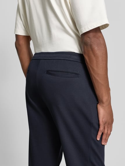 Männermodel draagt Stoffhose met achterzakken van MCNEAL in donkerblauw, rechte snit, zuivere viscose, detailopname achterkant.