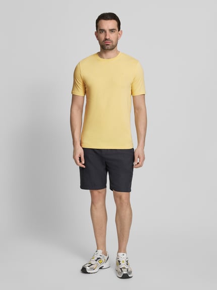 Männermodel trägt Regular Fit T-Shirt mit Logo-Stitching von Scotch & Soda in Gelb, Reine Baumwolle, Rundhalsausschnitt, Ganzkörperansicht von vorne.