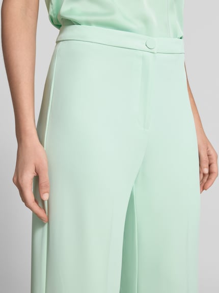 Vrouwenmodel draagt Stoffhose mit Bügelfalte van Rinascimento in mintgroen, wide leg fit, lichte stretch, materiaalmix, detailopname heupen.