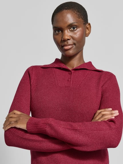 Frauenmodel trägt Sim Fit Pullover aus Viskose-Mix von Christian Berg Woman in Rot, Strick-Optik, Troyer-Kragen, Nahaufnahme Oberkörper.