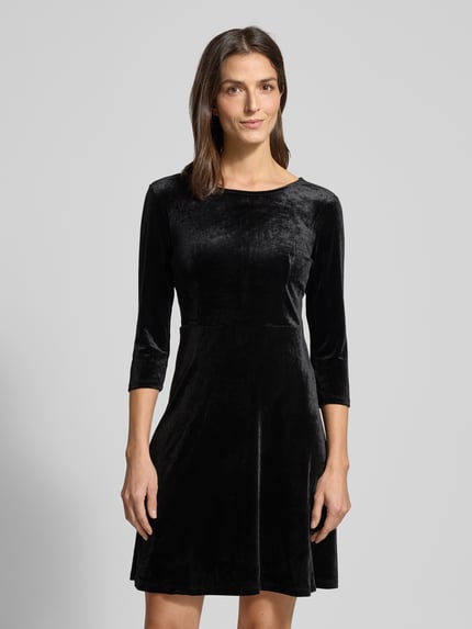 Vrouwenmodel draagt Minikleid met 3/4-mouwen model 'VEFLY' van Vila, zwart fluweel, getailleerd, ronde hals, voorkant bovenlichaam close-up.