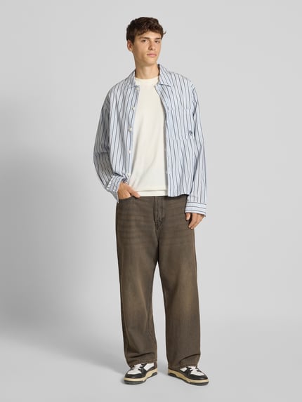 Männermodel trägt Baggy Fit Jeans im Used-Look von JACK & JONES in Braun mit Eingrifftaschen, reine Baumwolle, Ganzkörperansicht von vorne.