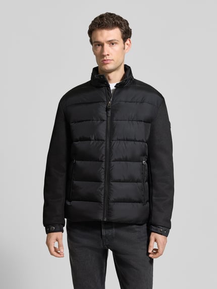 Männermodel trägt schwarze Regular Fit Steppjacke mit Stehkragen Modell 'Ciscos' von JOOP! COLLECTION, Ganzkörperansicht von vorne.