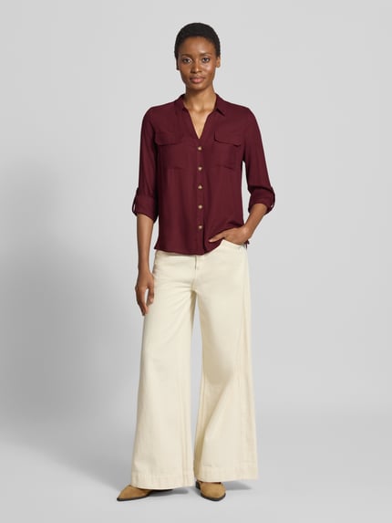 Frauenmodel trägt Regular Fit Langarmbluse aus reiner Viskose Modell 'BUMPY' von VERO MODA in Dunkelrot zu weiter, heller Hose, Ganzkörperansicht von vorne. Damen Langarmbluse von VERO MODA.