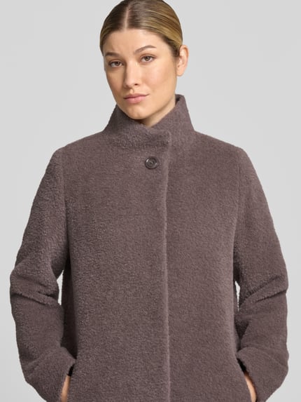 Kobieta nosi Mantel aus Schurwolle-Alpaka-Mix mit Stehkragen od ICONS Cinzia Rocca, krój regular fit, beżowy, tekstura boucle, zapięcie na guziki, kieszenie na ręce, szerokość w rozmiarze 36: 44 cm (ramiona), 51 cm (biust), długość pleców 89 cm, długość rękawa 66 cm, ujęcie z przodu, zbliżenie na górną część ciała.