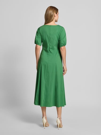 Frauenmodel trägt Midikleid mit Raffungen von More & More in Grün, taillierte Passform, Baumwoll-Mix, Halbarm, Rückenansicht Ganzkörperansicht.