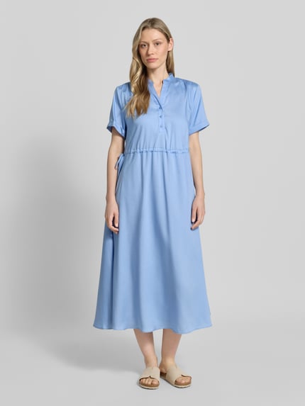 Frauenmodel trägt Midikleid aus Lyocell mit V-Ausschnitt von More & More in Hellblau, regulierbares Taillenband, A-Linie, Stehkragen, Knopfleiste, kurze Ärmel mit Aufschlag, Rückenlänge 123 cm, Brustweite 52 cm, Ärmellänge 21 cm, Ganzkörperansicht von vorne.
