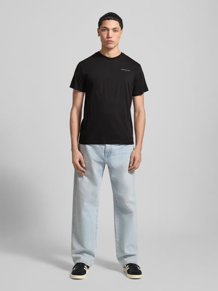 Männermodel trägt Slim Fit T-Shirt aus reiner Baumwolle Modell 'LINEAR CHEST TEE' von Tommy Jeans, Optik: Unifarben, Regular-Fit, Label-Print, Rundhals, Ärmelform: Kurzarm, aus Reine Baumwolle, Ganzkörperansicht von vorne.