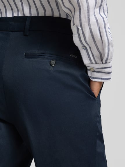 Männermodel trägt Slim Fit Hose aus Baumwoll-Mix Modell 'H-GENIUS' von BOSS in Dunkelblau, Twill-Struktur, Detailaufnahme Rückansicht.
