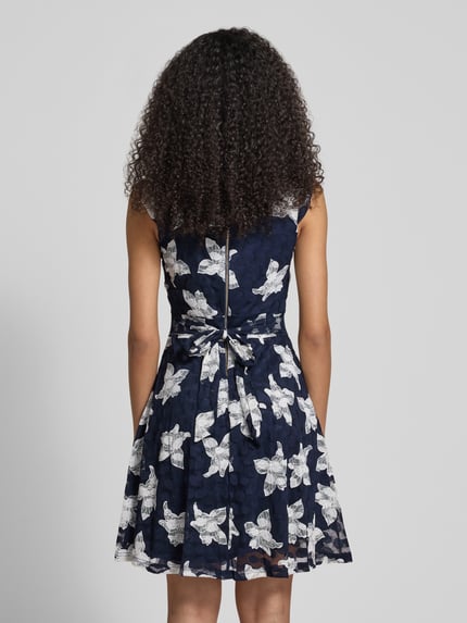 Vrouwenmodel draagt Mini-jurk im Allover-Look met ronde hals van Apricot, materiaalmix met stretch, A-lijn, ruglengte maat S 88 cm, borstwijdte maat S 40 cm, all-over dessin, donkerblauw met witte bloemen, rugaanzicht.