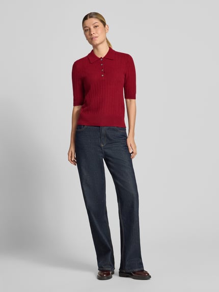 Frauenmodel trägt Slim Fit Poloshirt aus reinem Kaschmir von Christian Berg Woman in Rot, Strick-Optik, kurzärmelig, Ganzkörperansicht von vorne.