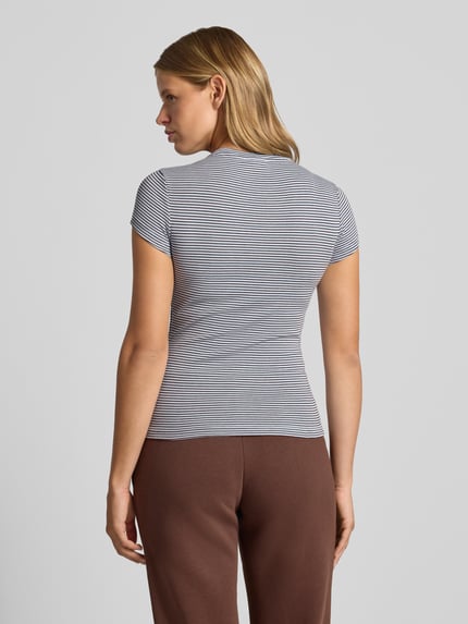 Frauenmodel trägt Skinny Fit T-Shirt aus Baumwoll-Mix von Gina Tricot mit feinen schwarz-weißen Streifen, Ganzkörperansicht Rückansicht. Rückenlänge bei Größe S: 54 cm, kurzärmliges Design, Rundhalsausschnitt, Baumwoll-Elasthan-Mix.